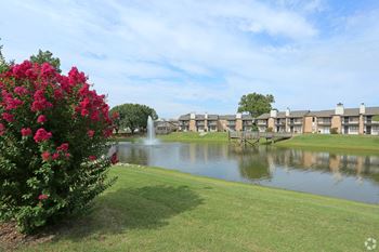 A beautiful view of a lake surrounded by buildings and a fountain.